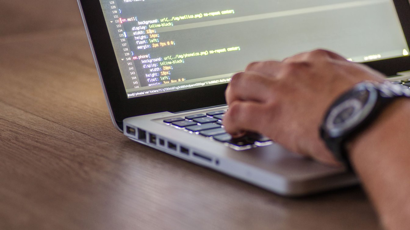 A developer typing code at a laptop