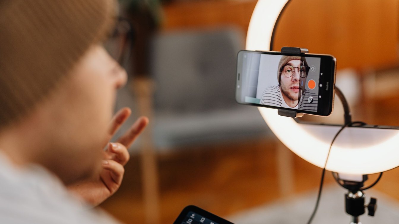 Adult man using a ring light and smartphone to record a video indoors